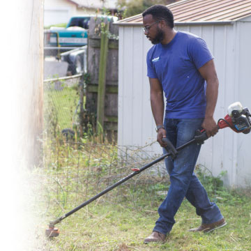 Chief Information Officer, Reggie Swanigan, working hard, weed eating for the community