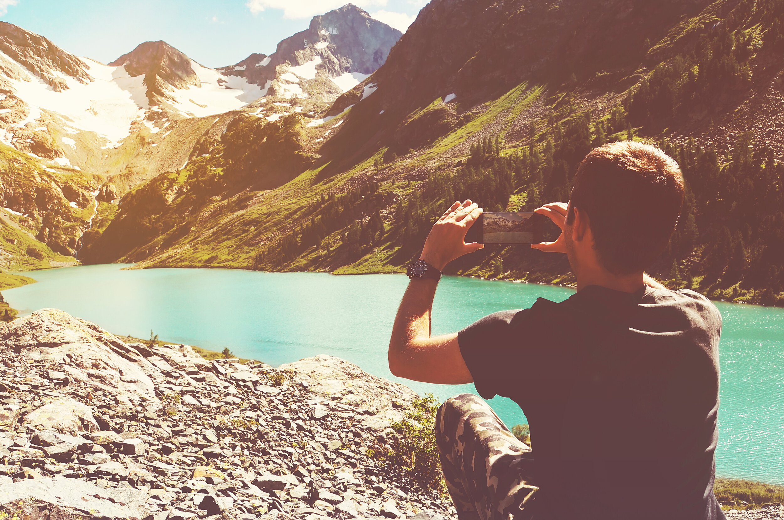 A man taking a photo of a scenic view in a mountainous area.