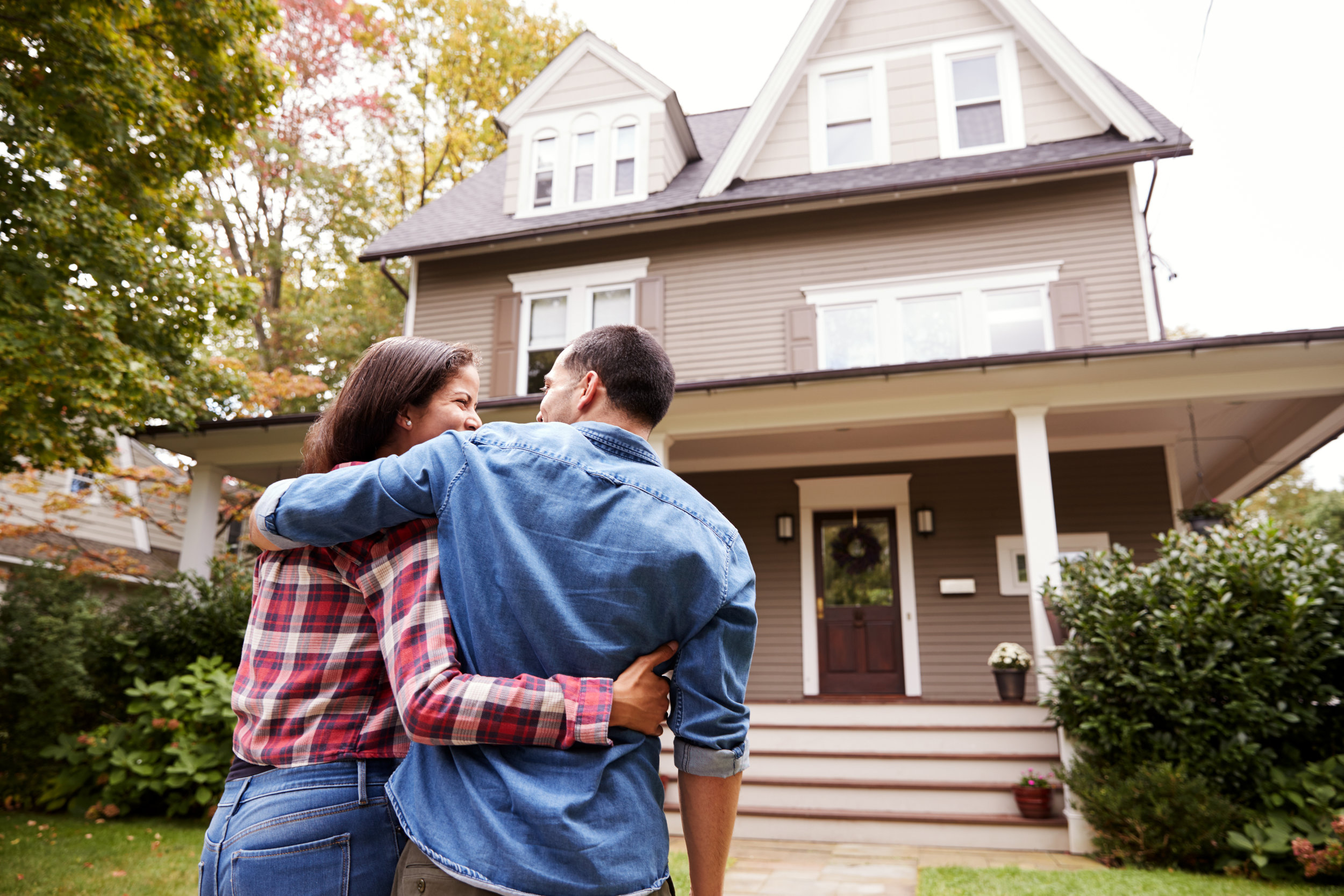 A couple embrace each other while facing toward their new house.