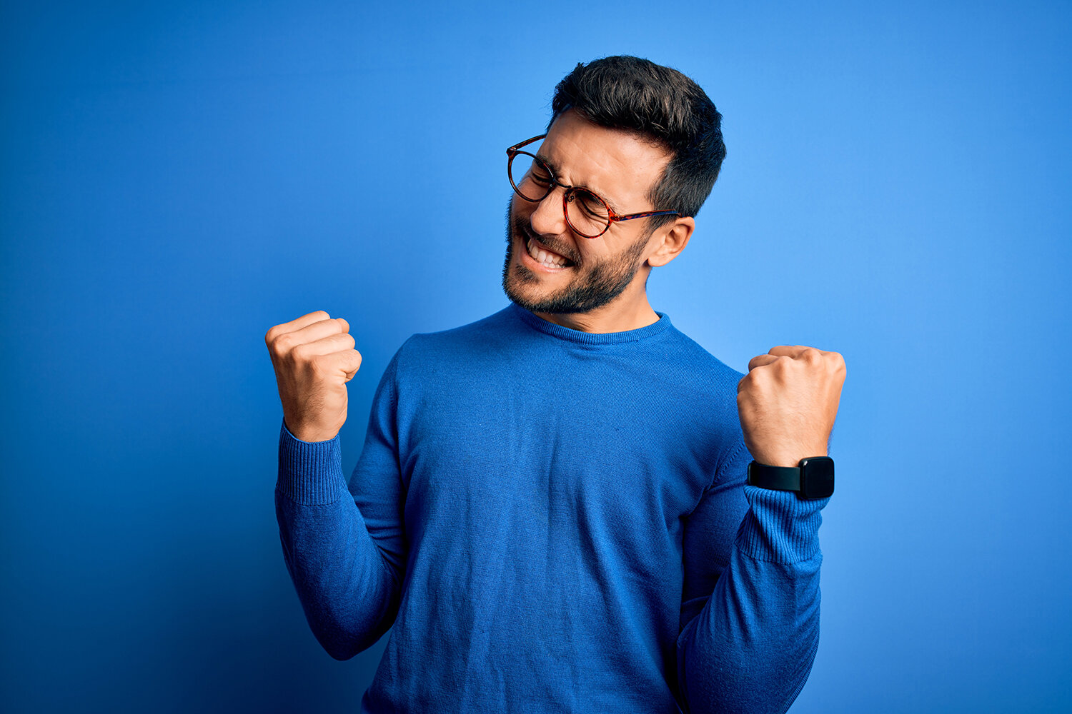A man with a blue shirt fist pumping in excitement.