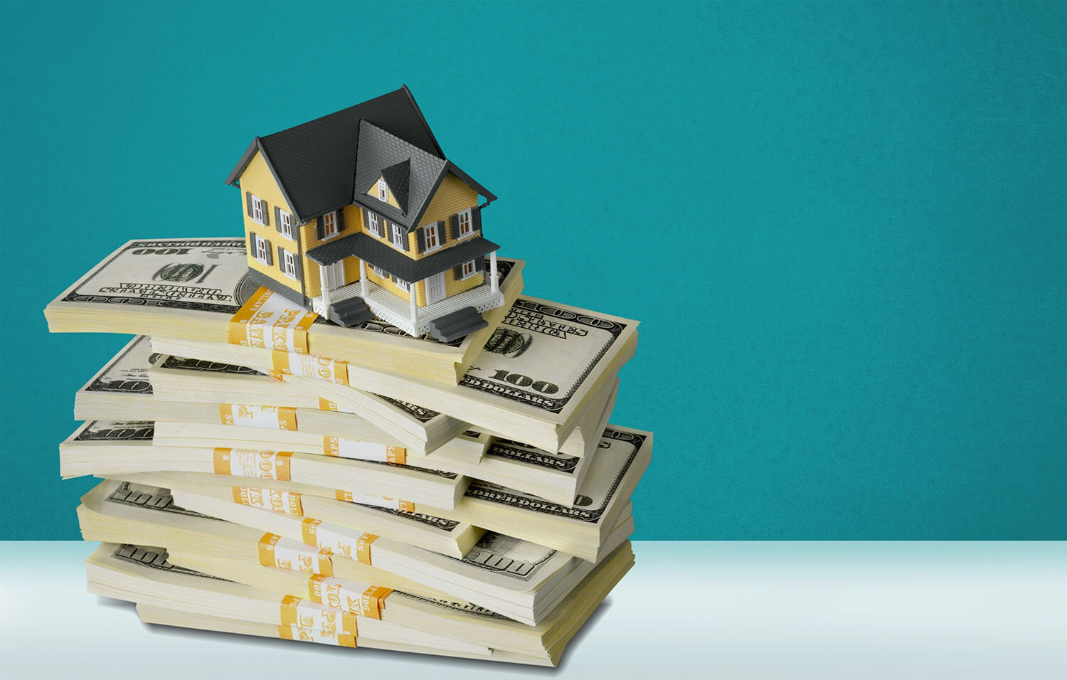 A stack of bundles of cash with a small house figurine on top.