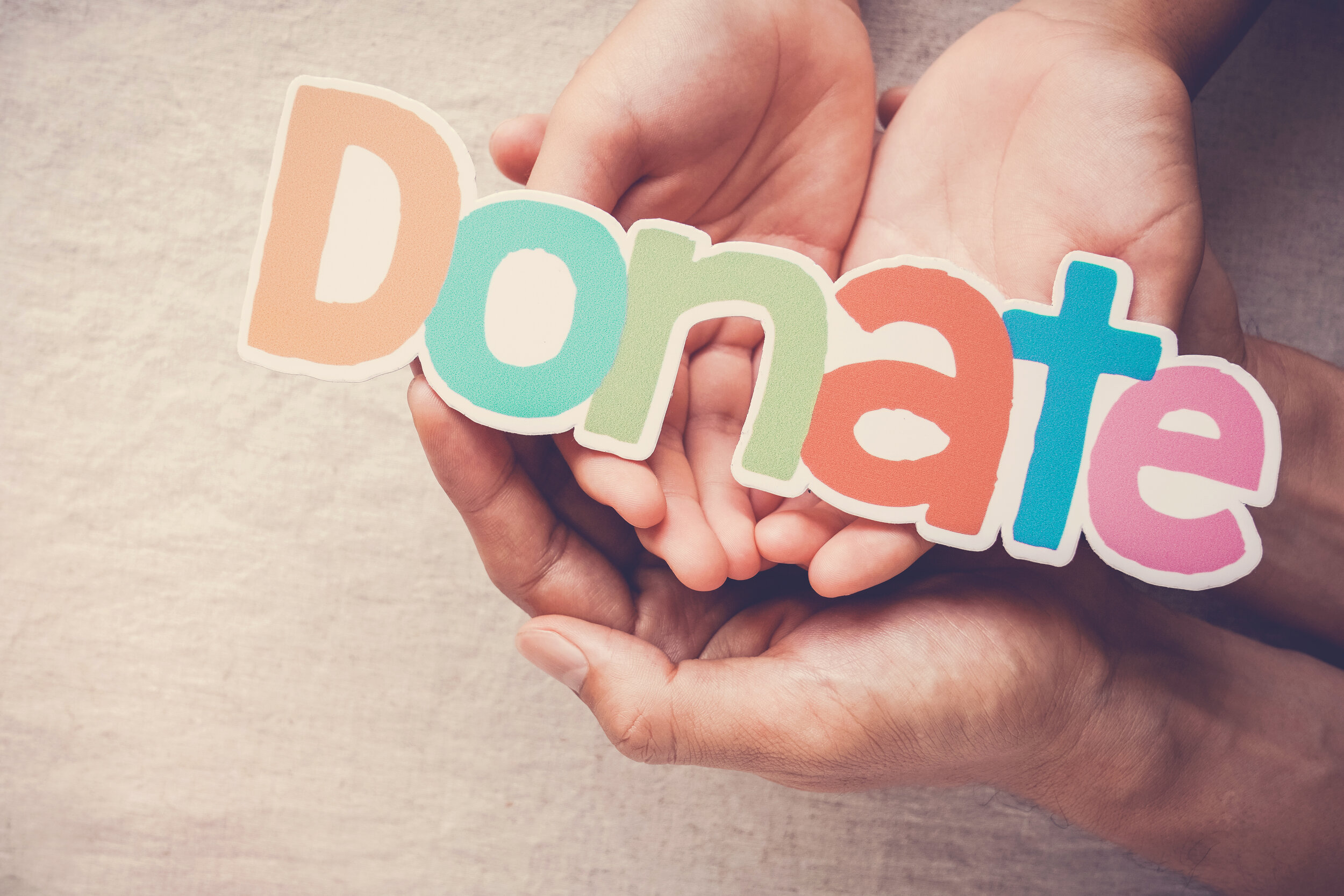 Several hands holding onto a sign that says