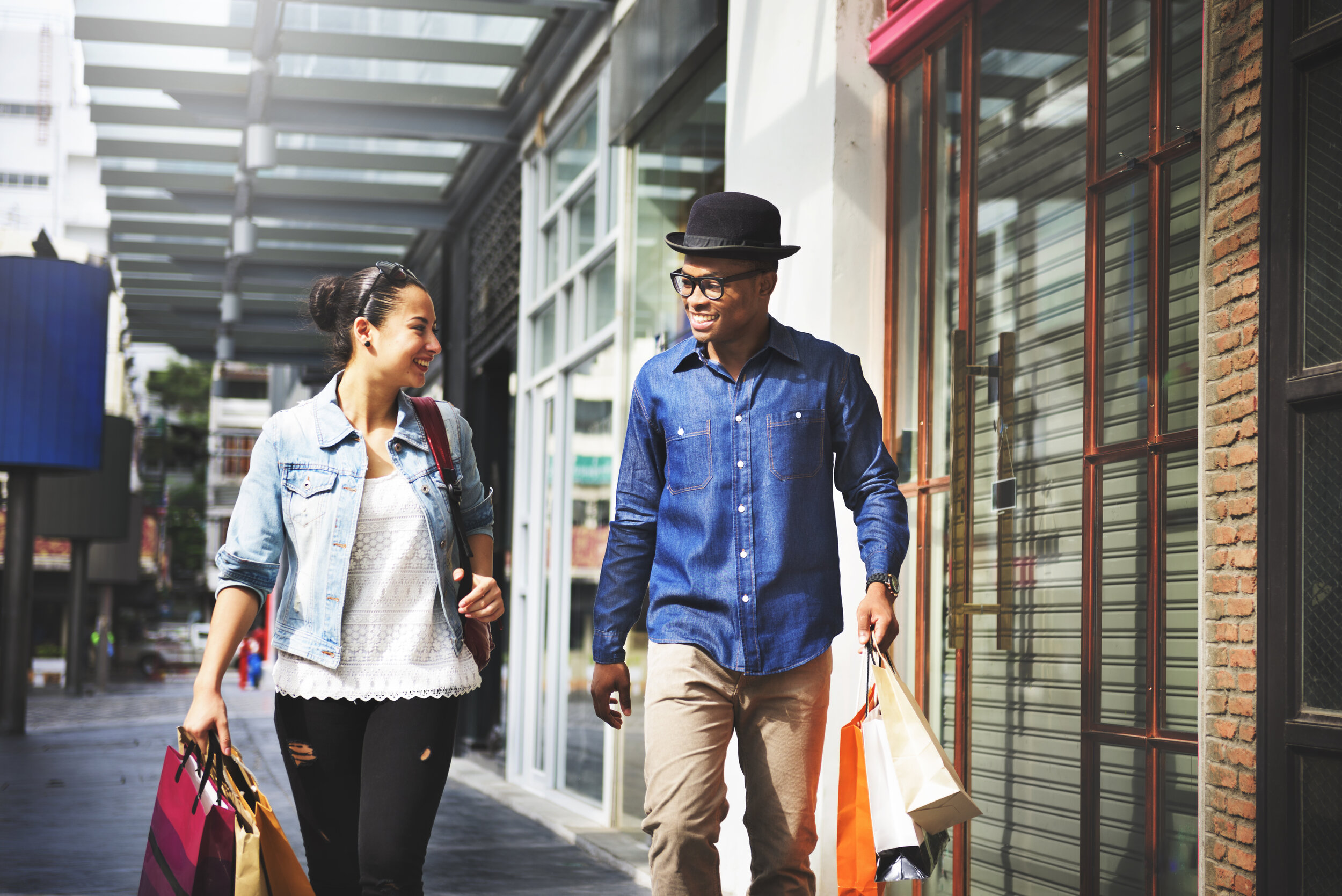 Two people holding their jackets, walking down the sidewalk.
