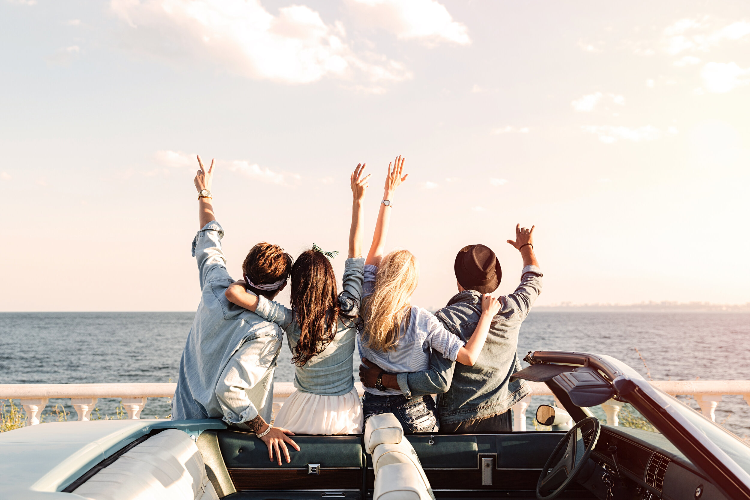 People cheering next to a car.