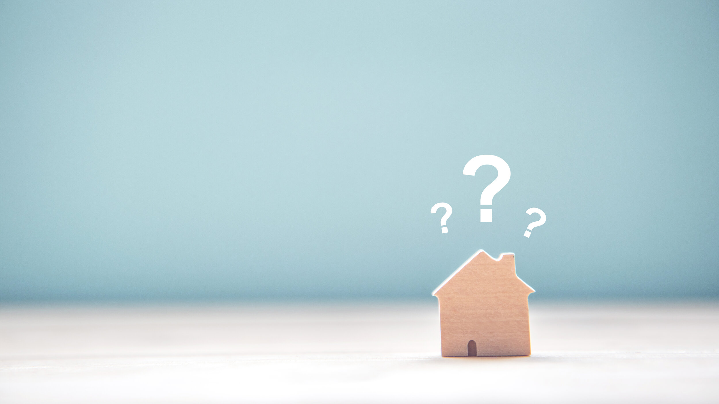 A tiny wooden house with question marks above it.