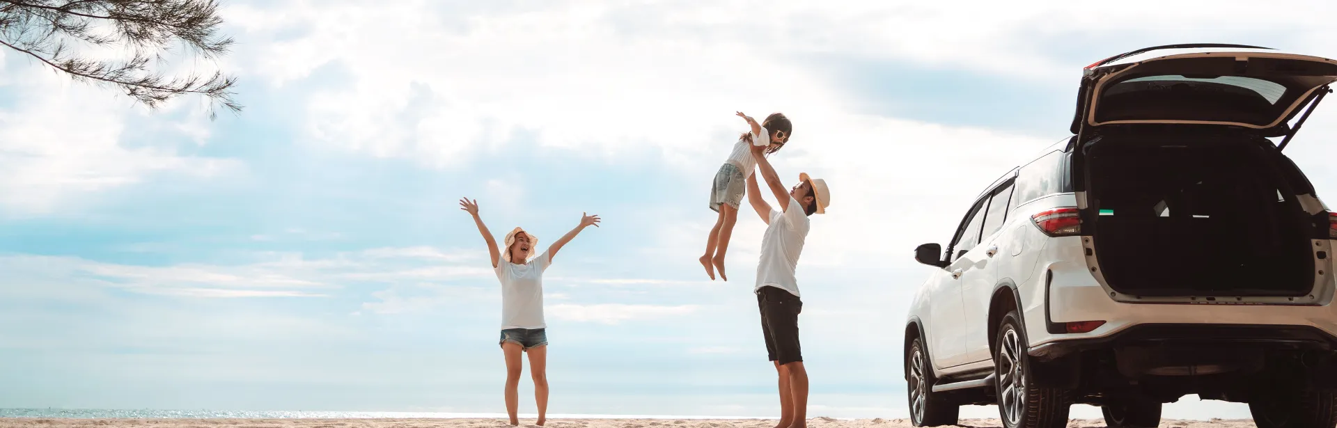 A family in an open plane celebrating, while a father throws child playfully up into the air.
