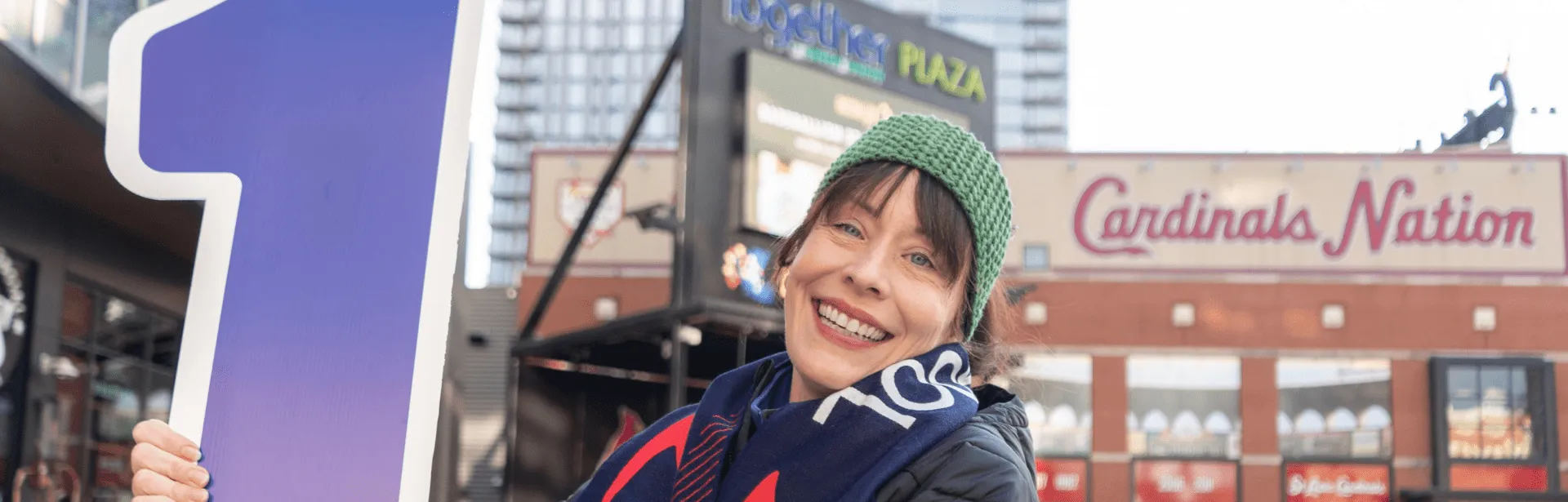 A woman smiling and holding a sign in an event area.