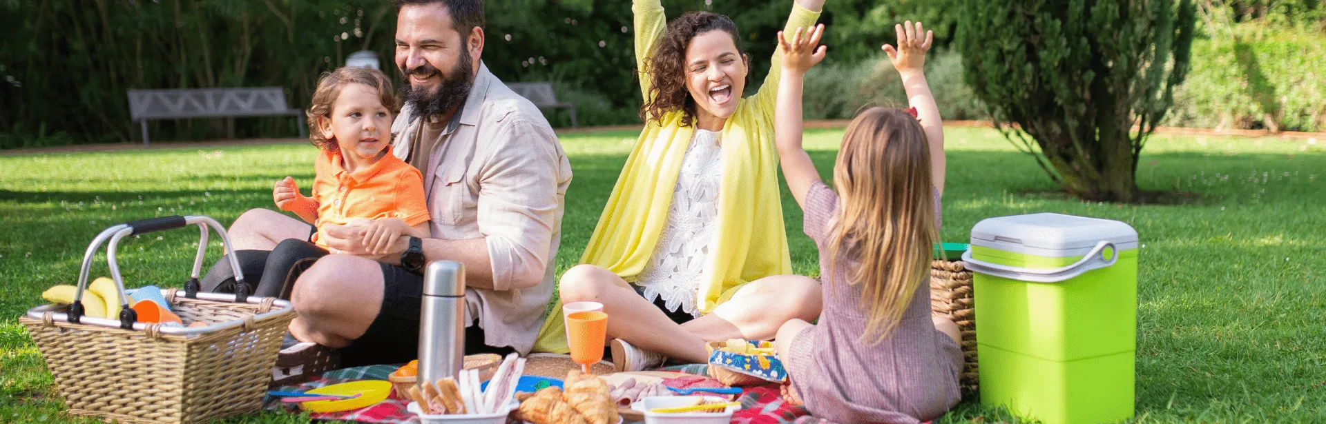 A family having a picnic in a park and smiling.