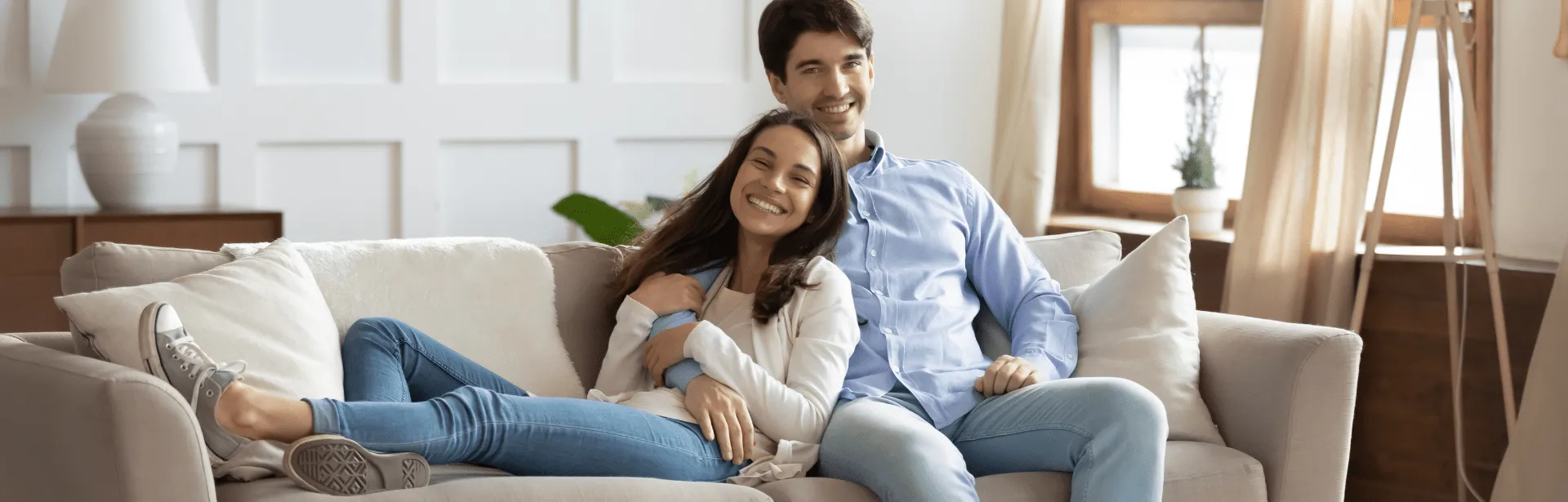 A woman leaning on a man while they sit on a couch.
